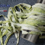 Fresh raw uncooked homemade green spinach pasta tagliatelle on wooden rolling pin over dark texture concrete background. Top view with space. Square image